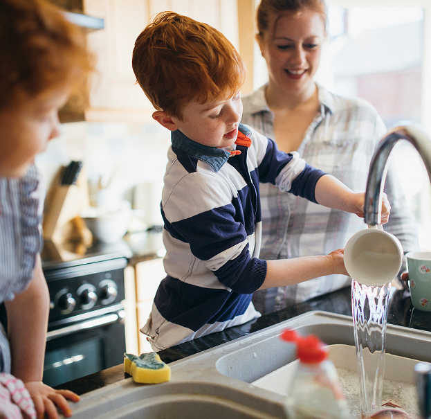 A white boy washing up a mug in the sink